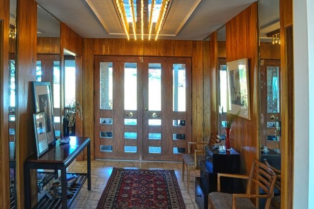 Cette photo montre un grand hall d'entrée rétro avec un sol en marbre, une porte double et une porte en bois brun.