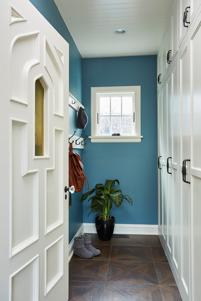 Ejemplo de vestíbulo posterior clásico con paredes azules, puerta simple, puerta blanca, suelo marrón y suelo de baldosas de porcelana