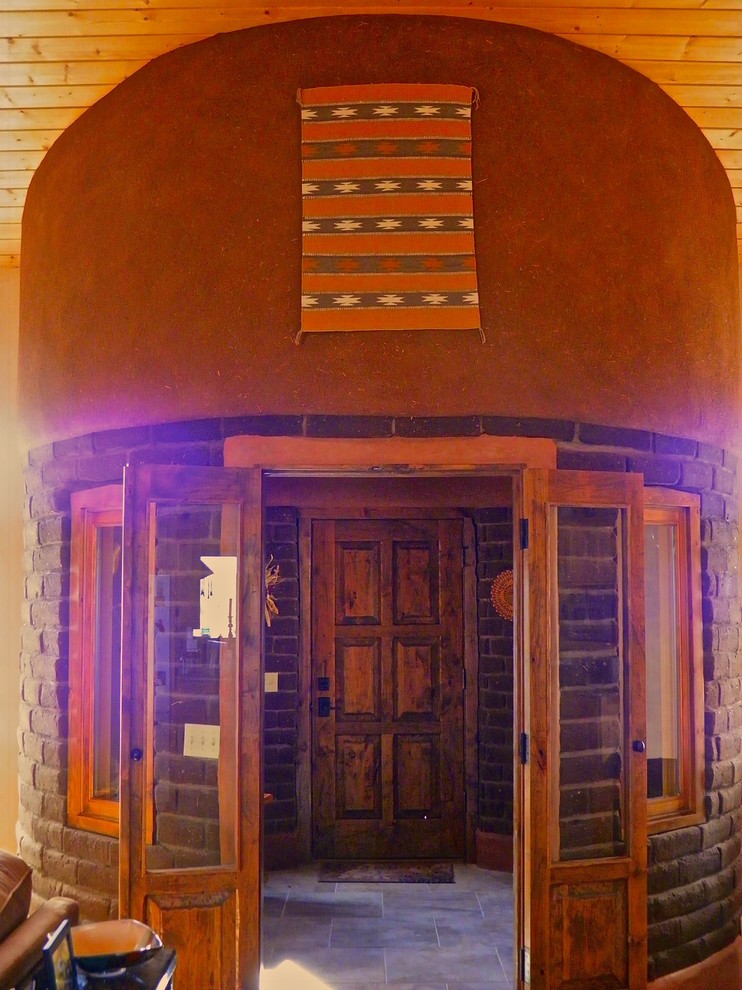 Пример оригинального дизайна: вестибюль среднего размера в стиле фьюжн с коричневыми стенами, полом из травертина, одностворчатой входной дверью и входной дверью из темного дерева