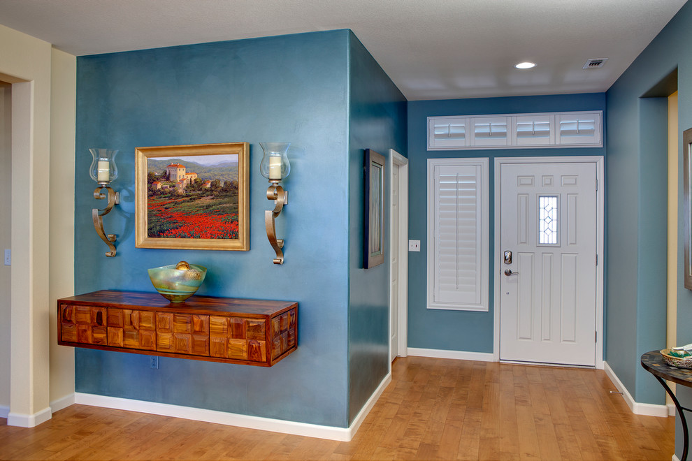 Exemple d'une porte d'entrée tendance de taille moyenne avec un mur bleu, un sol en bois brun, une porte simple et une porte blanche.