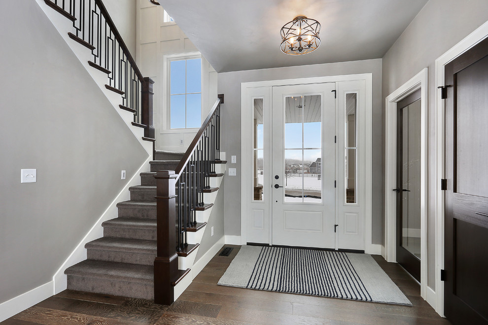 Idee per un ingresso tradizionale con pareti grigie, pavimento in legno massello medio, una porta singola, una porta bianca e pavimento marrone