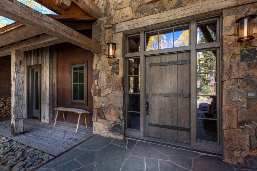 This is an example of a medium sized rustic front door in Denver with a single front door and a dark wood front door.