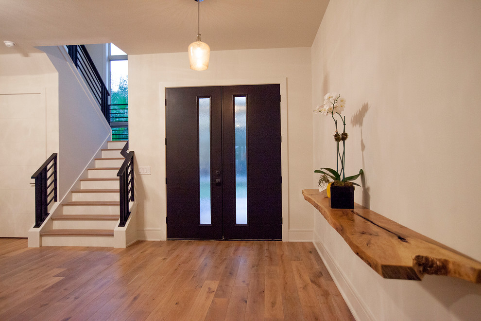 Idée de décoration pour un très grand hall d'entrée minimaliste avec un mur beige, parquet clair, une porte double et une porte en bois foncé.