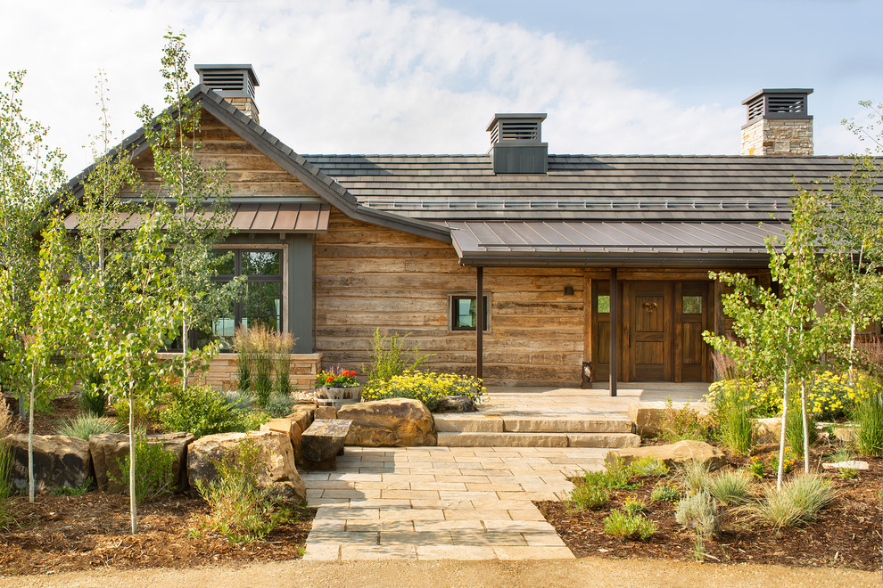 Réalisation d'une porte d'entrée chalet avec un mur marron, une porte simple, une porte en bois brun et un sol beige.