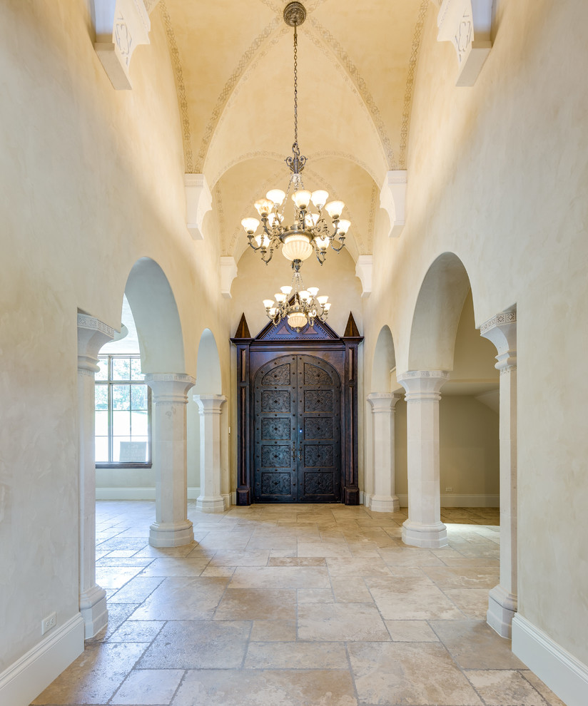Пример оригинального дизайна: огромная узкая прихожая в средиземноморском стиле с бежевыми стенами, полом из травертина, двустворчатой входной дверью, входной дверью из темного дерева и бежевым полом