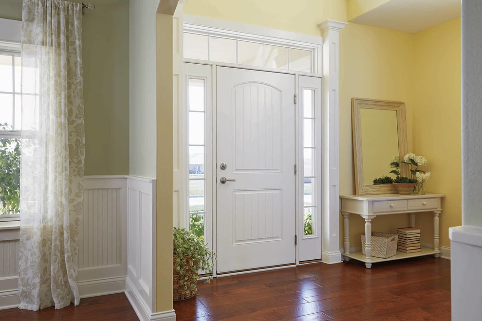 Inredning av en shabby chic-inspirerad mellanstor ingång och ytterdörr, med gula väggar, mörkt trägolv, en enkeldörr, en vit dörr och brunt golv