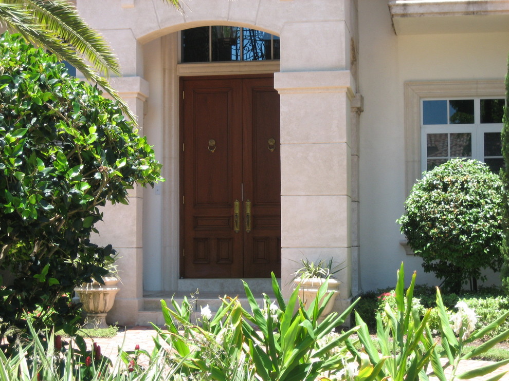 Example of a large tuscan marble floor entryway design in Miami with a medium wood front door and white walls