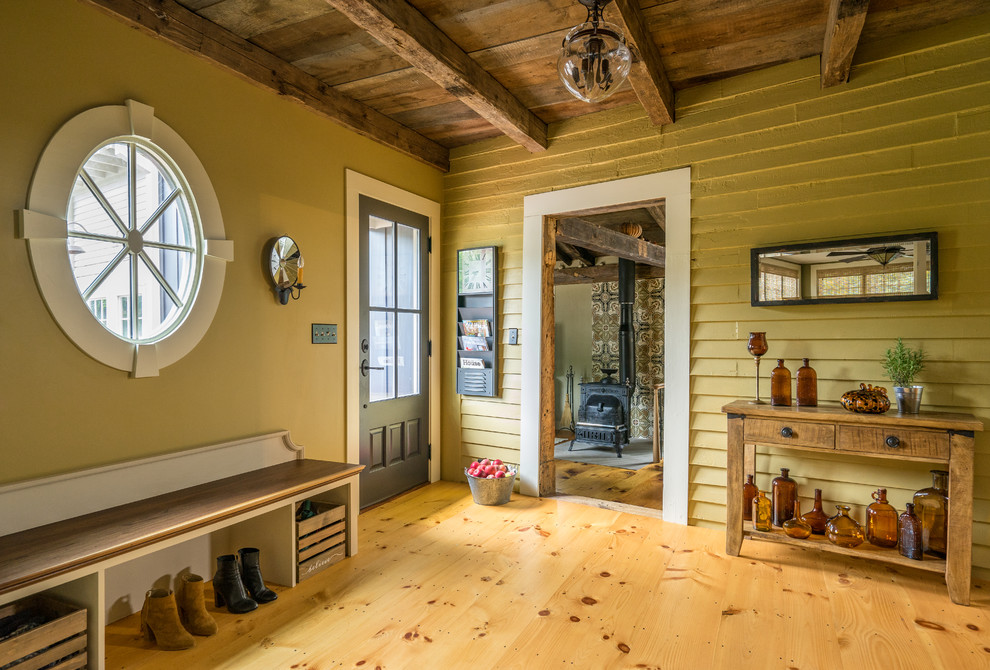 Diseño de distribuidor de estilo de casa de campo con paredes amarillas, suelo de madera en tonos medios, puerta simple y suelo marrón