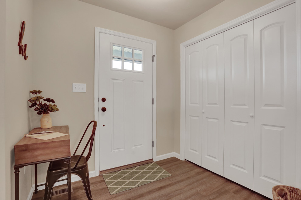 Esempio di un corridoio minimal di medie dimensioni con pareti beige, pavimento in vinile, una porta singola, una porta bianca e pavimento marrone