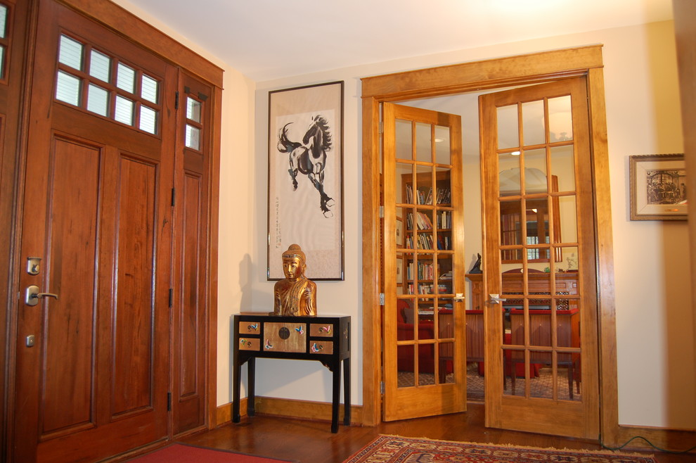 Immagine di un ingresso o corridoio stile americano con pavimento in legno massello medio, pareti beige, una porta in legno bruno e una porta singola