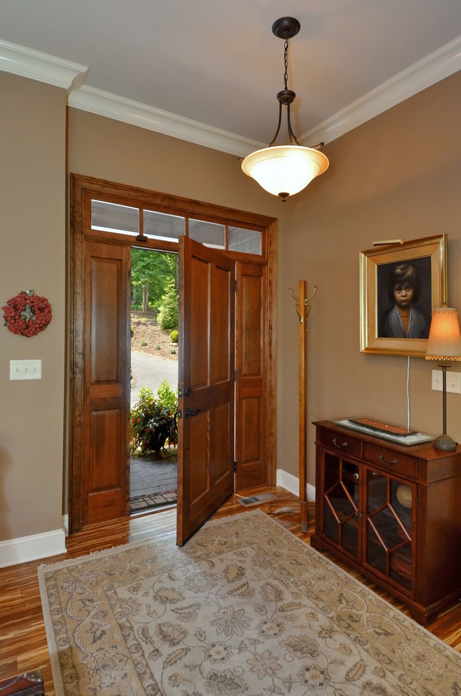 Minimalist medium tone wood floor entryway photo in Other with beige walls and a dark wood front door