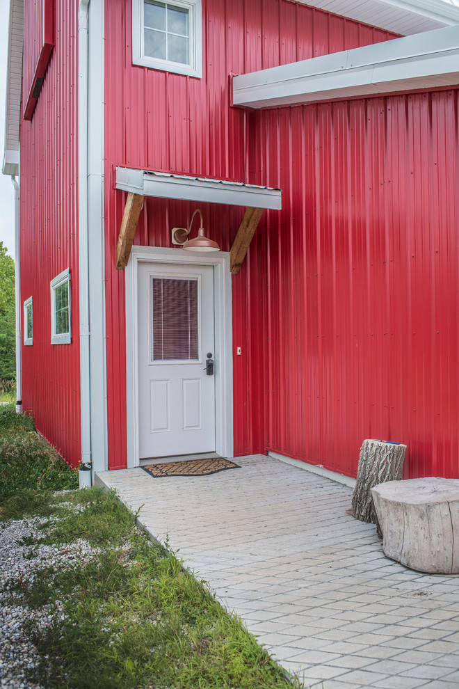 Imagen de puerta principal campestre de tamaño medio con paredes rojas, suelo de cemento, puerta simple y puerta blanca