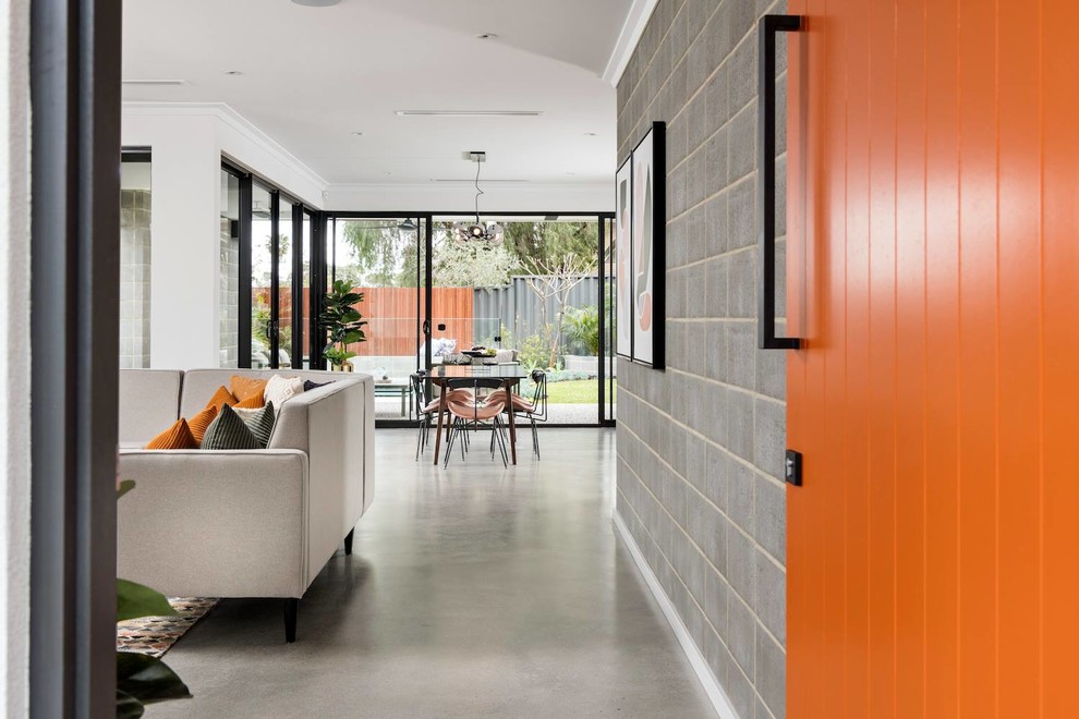 Inspiration för en stor funkis ingång och ytterdörr, med grå väggar, betonggolv, en pivotdörr, en orange dörr och grått golv