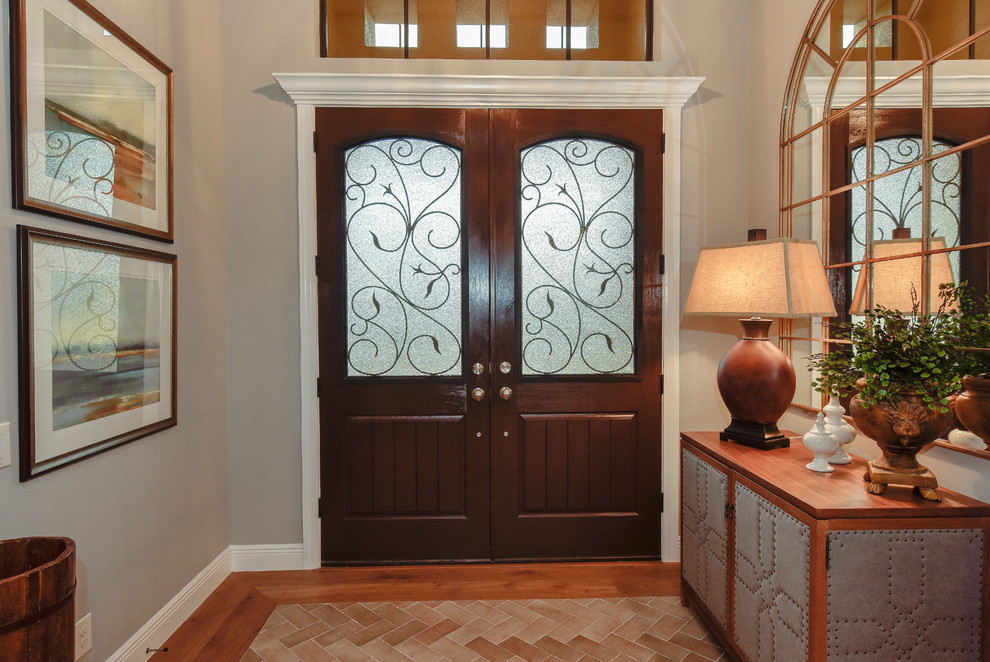 Modelo de puerta principal tradicional de tamaño medio con paredes grises, suelo de madera en tonos medios, puerta doble y puerta de madera oscura