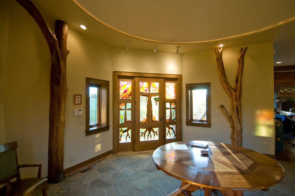 Exemple d'un grand hall d'entrée montagne avec un sol en ardoise, un mur beige, une porte en bois brun et une porte simple.