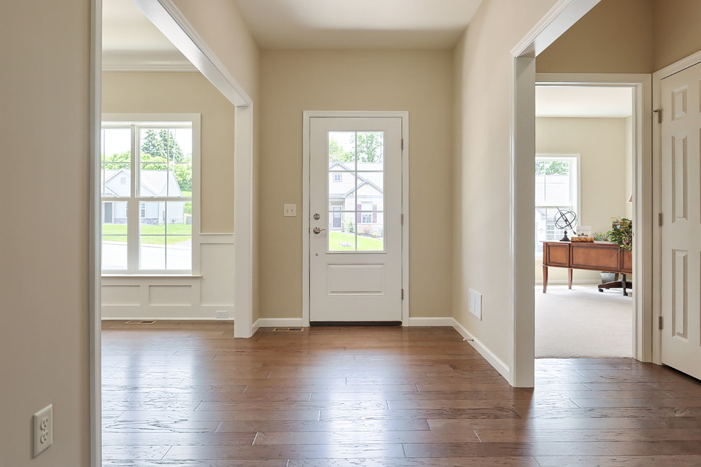 Diseño de puerta principal clásica grande con paredes beige y suelo de madera en tonos medios