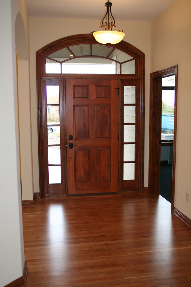 Klassisches Foyer mit beiger Wandfarbe, braunem Holzboden, Einzeltür und hellbrauner Holzhaustür in Milwaukee