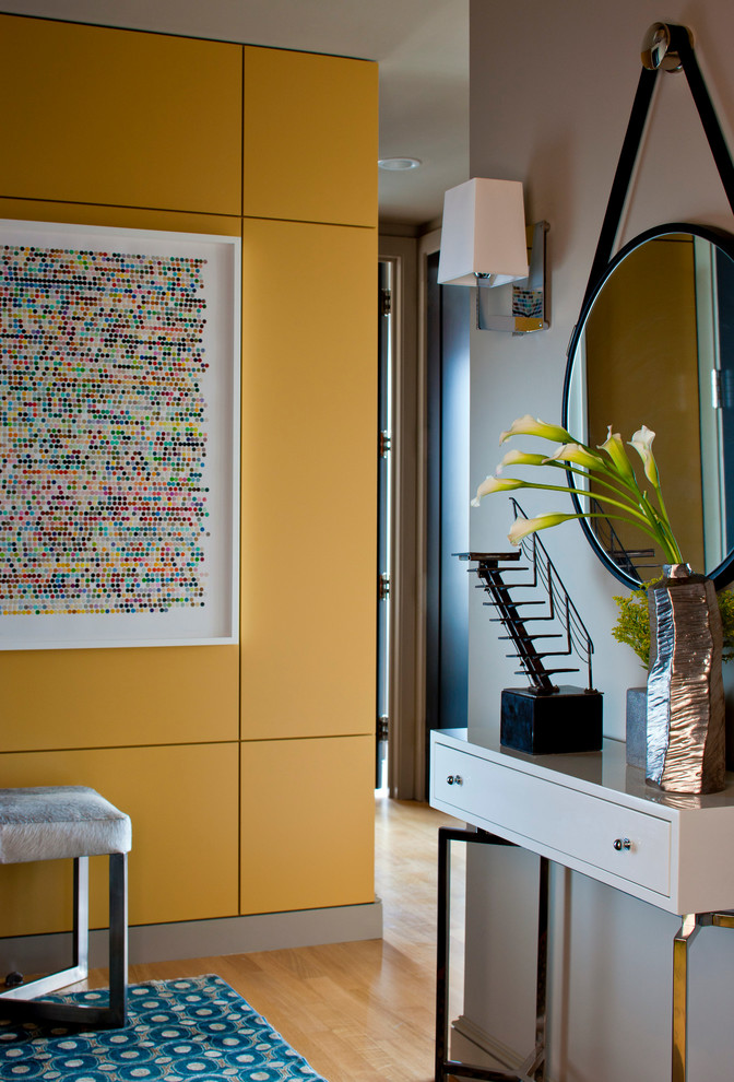 Réalisation d'un grand hall d'entrée design avec un mur jaune et parquet clair.