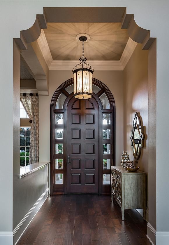 Idée de décoration pour une entrée tradition de taille moyenne avec un couloir, un mur beige, parquet foncé, une porte simple, une porte en bois foncé et un sol marron.