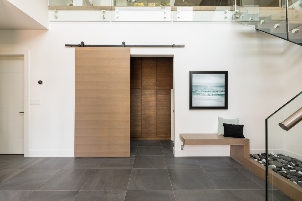 Großes Modernes Foyer mit weißer Wandfarbe, Keramikboden, Drehtür, schwarzer Haustür und grauem Boden in Vancouver