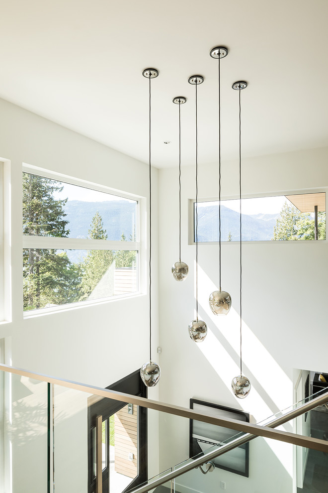 This is an example of a large contemporary foyer in Vancouver with white walls, ceramic flooring, a pivot front door, a black front door and grey floors.