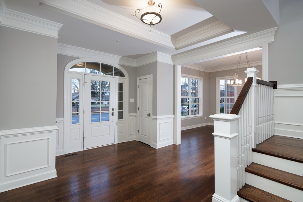 Klassisches Foyer mit grauer Wandfarbe, Einzeltür, braunem Boden, eingelassener Decke, vertäfelten Wänden und weißer Haustür in Baltimore