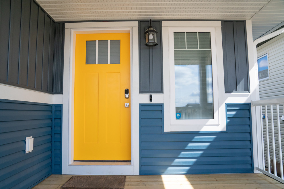 Идея дизайна: маленькая входная дверь в стиле кантри с синими стенами, одностворчатой входной дверью и желтой входной дверью для на участке и в саду