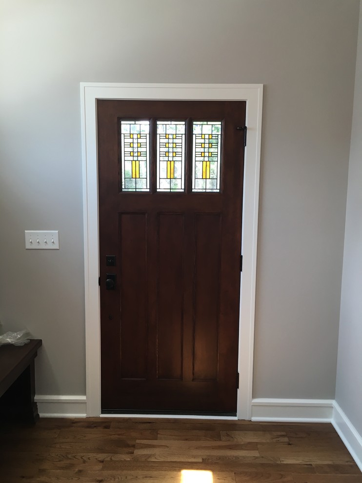 Aménagement d'une porte d'entrée craftsman de taille moyenne avec un mur gris, parquet foncé, une porte simple et une porte en bois foncé.