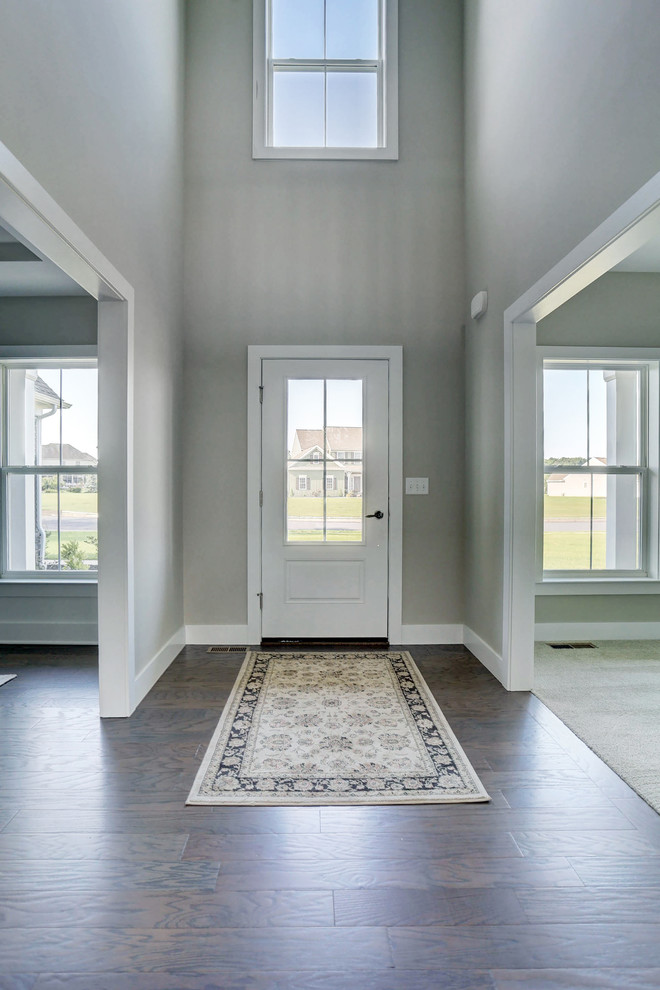 Ejemplo de distribuidor de estilo americano grande con paredes beige, suelo de madera en tonos medios, puerta simple y puerta blanca