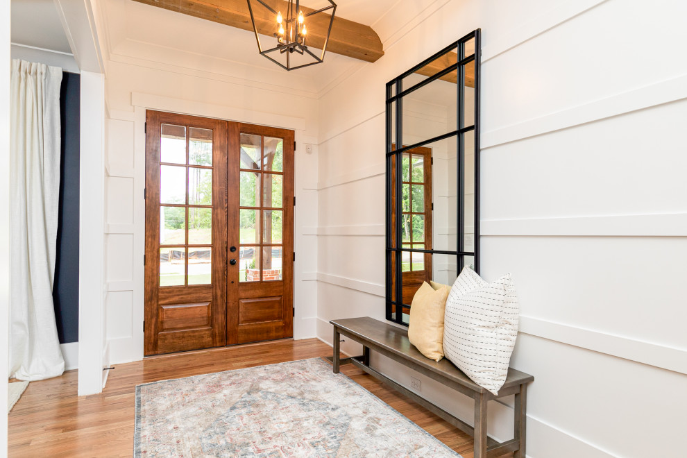 Mittelgroßes Landhaus Foyer mit weißer Wandfarbe, braunem Holzboden, Doppeltür, hellbrauner Holzhaustür, braunem Boden, freigelegten Dachbalken und vertäfelten Wänden in Atlanta