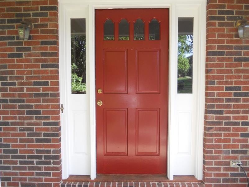 Exemple d'une porte d'entrée nature avec une porte simple et une porte rouge.