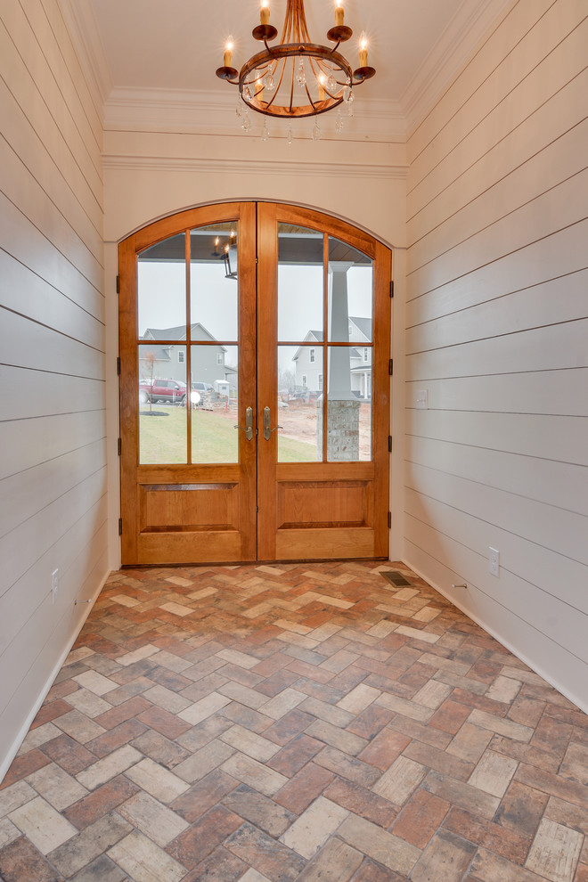Idee per un ingresso stile americano di medie dimensioni con pareti bianche, pavimento in mattoni, una porta a due ante e una porta in legno bruno