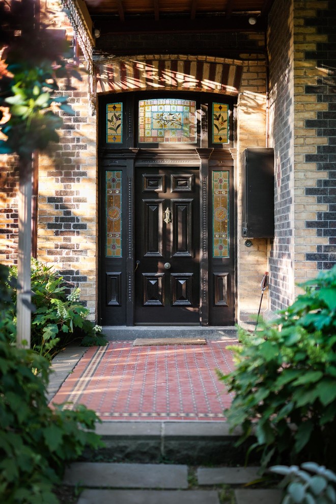На фото: входная дверь в стиле неоклассика (современная классика) с одностворчатой входной дверью и черной входной дверью с