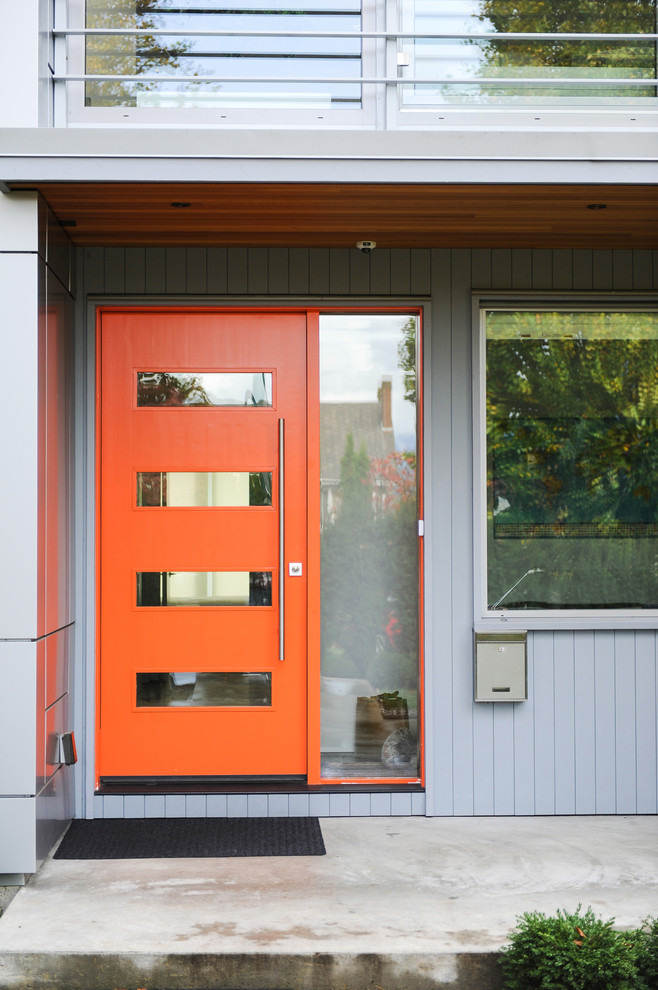 На фото: входная дверь среднего размера в современном стиле с серыми стенами, бетонным полом, одностворчатой входной дверью и оранжевой входной дверью
