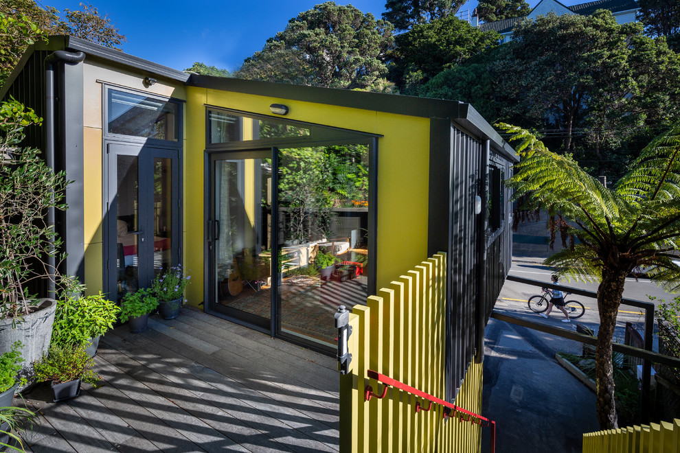 Cette image montre une petite porte d'entrée urbaine avec un mur vert et une porte coulissante.