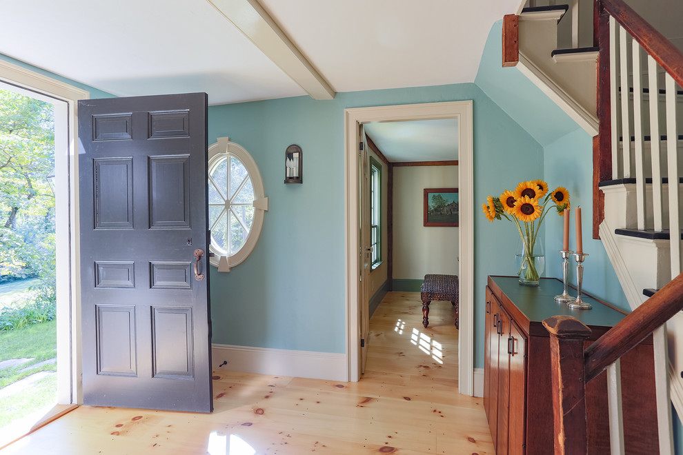 Idee per un piccolo ingresso country con pareti blu, parquet chiaro, una porta singola e una porta nera