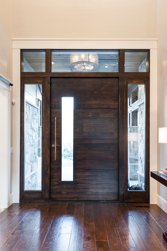 На фото: входная дверь среднего размера в стиле неоклассика (современная классика) с серыми стенами, темным паркетным полом, поворотной входной дверью и входной дверью из темного дерева с