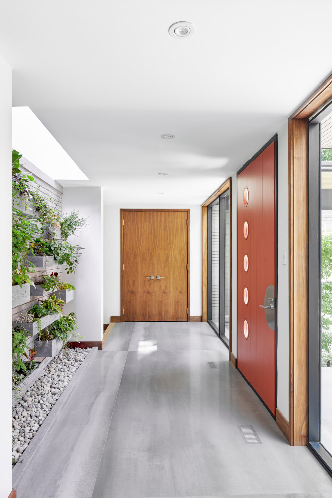 This is an example of a medium sized contemporary hallway in Toronto with white walls, a single front door, an orange front door and grey floors.