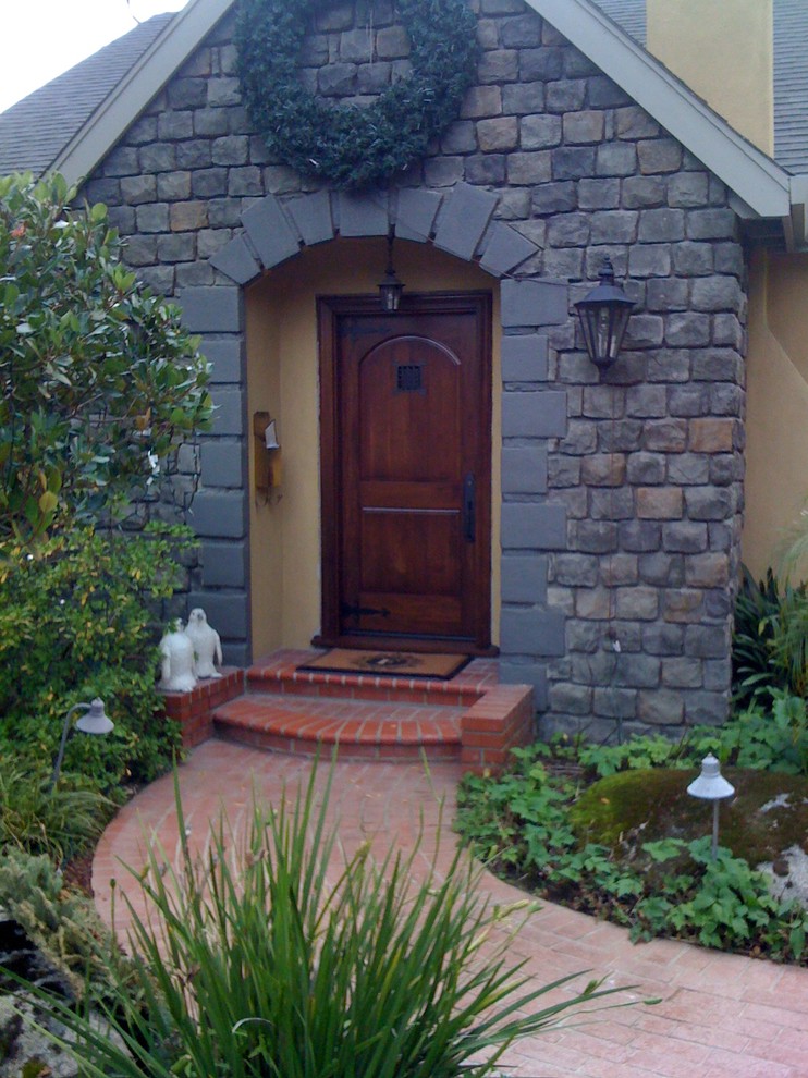 На фото: маленькая входная дверь в стиле рустика с бежевыми стенами, кирпичным полом, одностворчатой входной дверью, входной дверью из темного дерева и красным полом для на участке и в саду