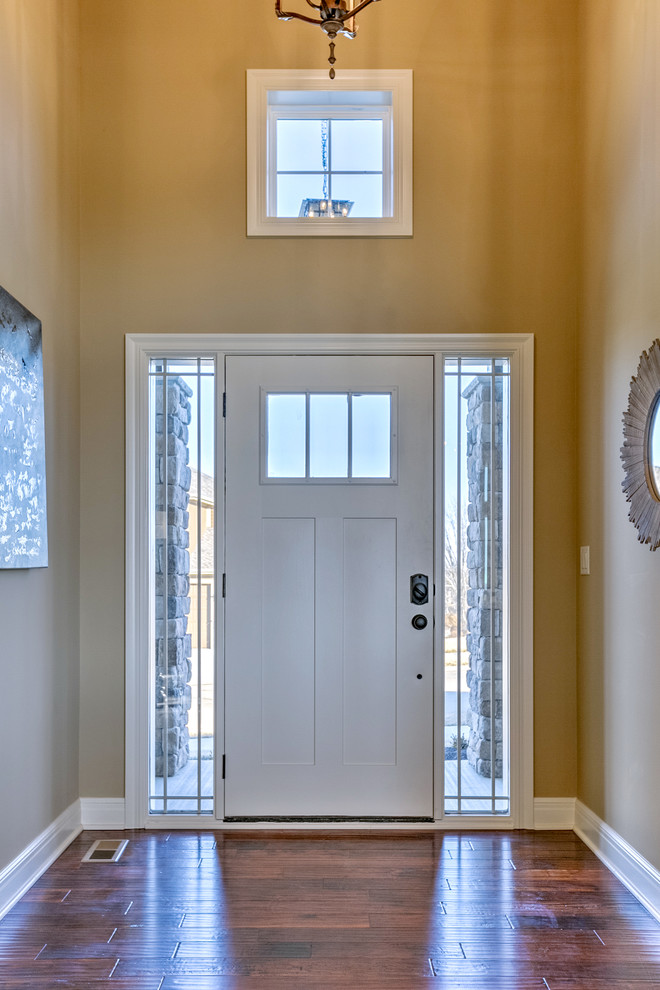 Ispirazione per un ingresso stile americano di medie dimensioni con una porta singola, pareti nere, pavimento in legno massello medio e una porta bianca