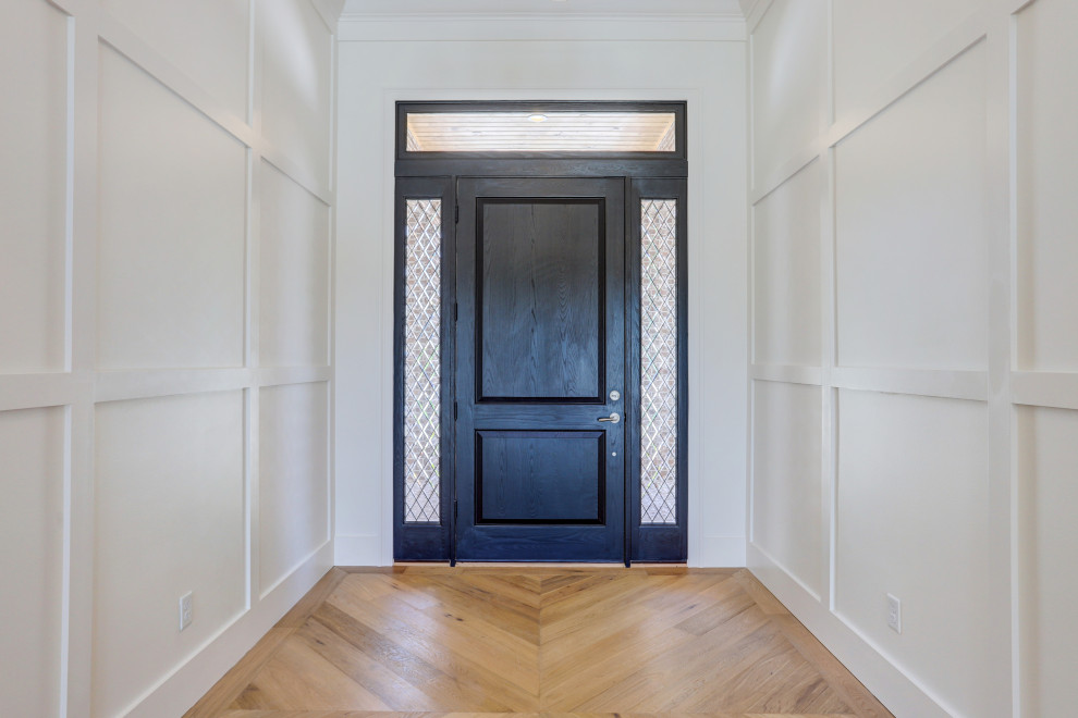 Cette image montre une grande porte d'entrée traditionnelle avec un mur blanc, parquet clair, une porte simple, une porte noire, un sol marron et un plafond décaissé.