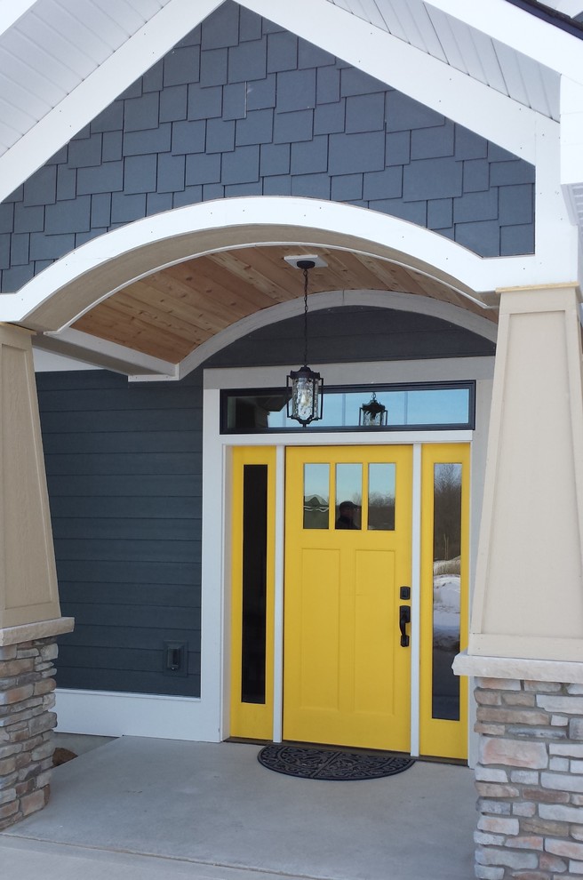 This is an example of a classic entrance in Grand Rapids with a yellow front door and feature lighting.