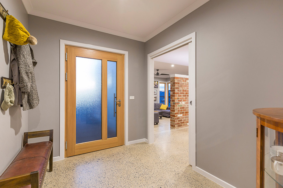 На фото: маленькая входная дверь в современном стиле с серыми стенами, бетонным полом, одностворчатой входной дверью и входной дверью из светлого дерева для на участке и в саду с