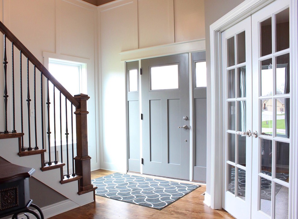 Arts and crafts light wood floor entryway photo in Kansas City with white walls and a gray front door