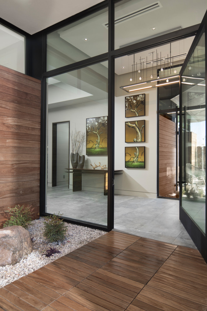 На фото: фойе среднего размера в современном стиле с серыми стенами, полом из керамогранита, поворотной входной дверью, стеклянной входной дверью и серым полом с