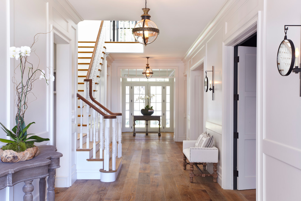 Inspiration for a large timeless medium tone wood floor and brown floor entry hall remodel in Los Angeles with white walls
