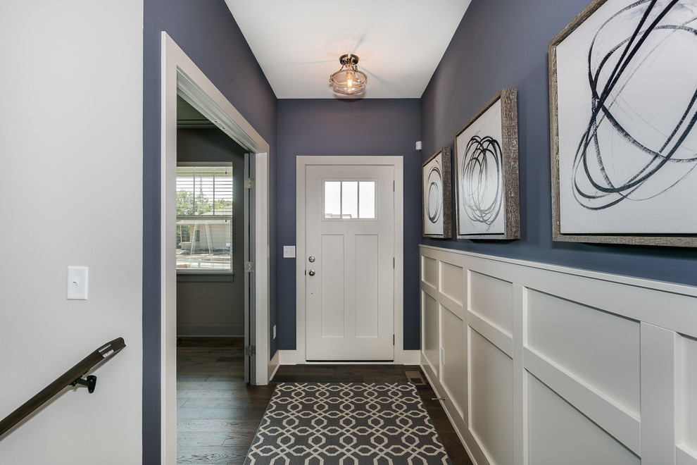 Cette image montre une entrée craftsman de taille moyenne avec un couloir, une porte simple, une porte blanche et parquet foncé.