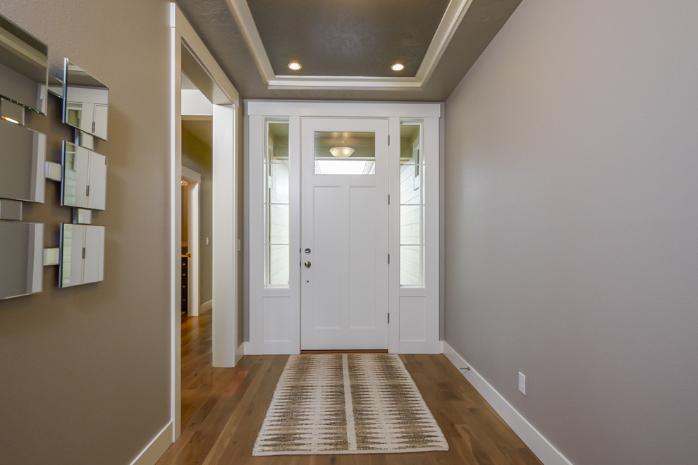 Ejemplo de puerta principal de estilo americano con paredes beige, suelo de madera clara, puerta simple y puerta blanca