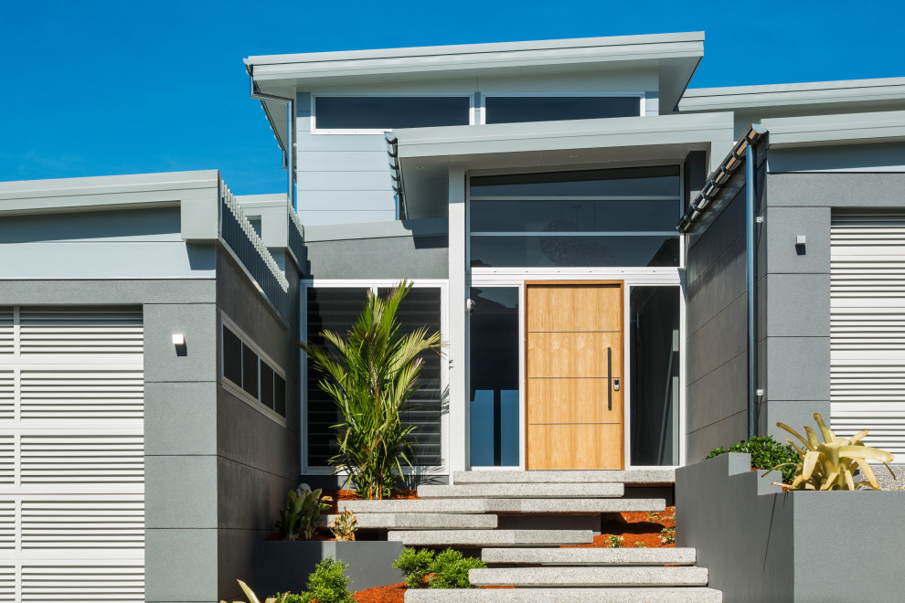 Moderne Haustür mit weißer Wandfarbe, Porzellan-Bodenfliesen, Drehtür, hellbrauner Holzhaustür und weißem Boden in Cairns