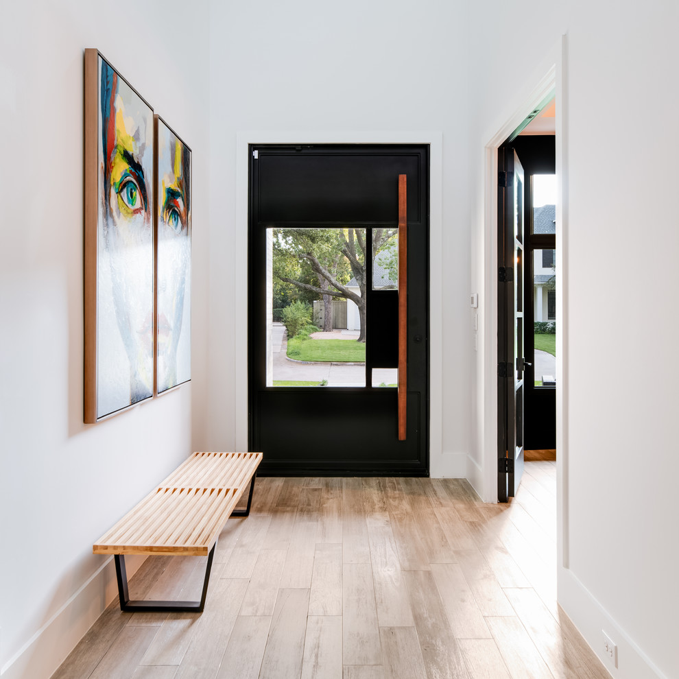 На фото: входная дверь среднего размера в современном стиле с черными стенами, светлым паркетным полом, поворотной входной дверью, черной входной дверью и серым полом с